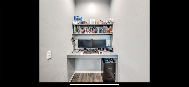 office area with built in desk, wood finished floors, baseboards, and a textured wall