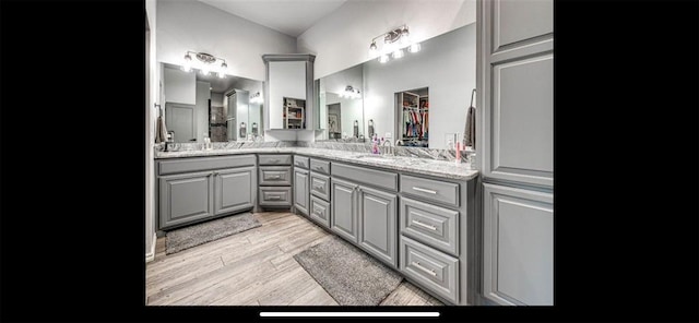 bathroom with double vanity, wood finished floors, and a sink
