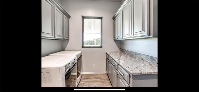 laundry room with baseboards, light wood-type flooring, cabinet space, and washer and clothes dryer