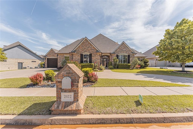 traditional-style house with curved driveway, a front lawn, a garage, and brick siding