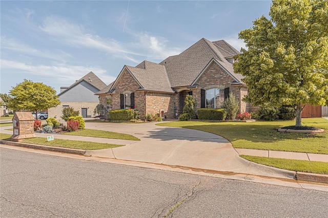 2612 SW 137th St, Oklahoma City, OK 73170 - french country home featuring brick siding, concrete driveway, a front yard, and a shingled roof
