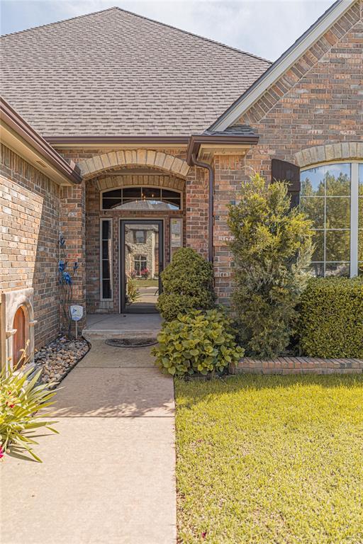 2612 SW 137th St, Oklahoma City, OK 73170 - view of exterior entry with brick siding, a shingled roof, and a lawn