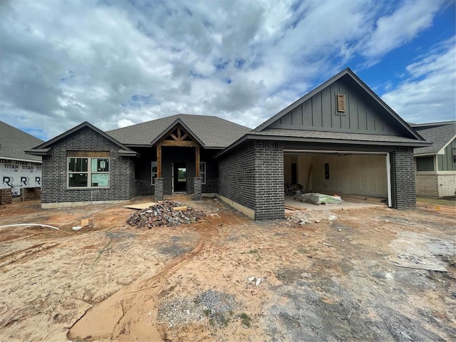 view of front of house featuring board and batten siding, brick siding, an attached garage, and driveway