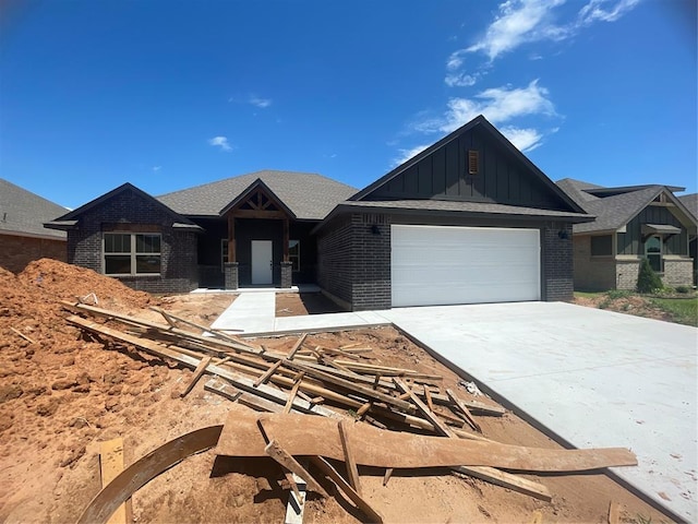 5012 Misty Wood Ln, Mustang, OK 73064 - view of front of property featuring board and batten siding, brick siding, a garage, and driveway