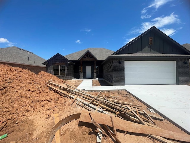 5012 Misty Wood Ln, Mustang, OK 73064 - view of front facade featuring board and batten siding, brick siding, driveway, and a garage