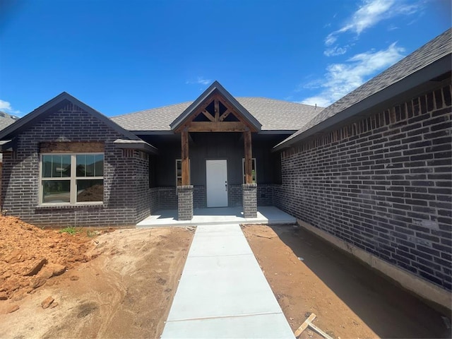 5012 Misty Wood Ln, Mustang, OK 73064 - doorway to property featuring brick siding and roof with shingles