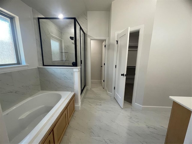 5012 Misty Wood Ln, Mustang, OK 73064 - bathroom featuring marble finish floors, a garden tub, a stall shower, vanity, and a spacious closet