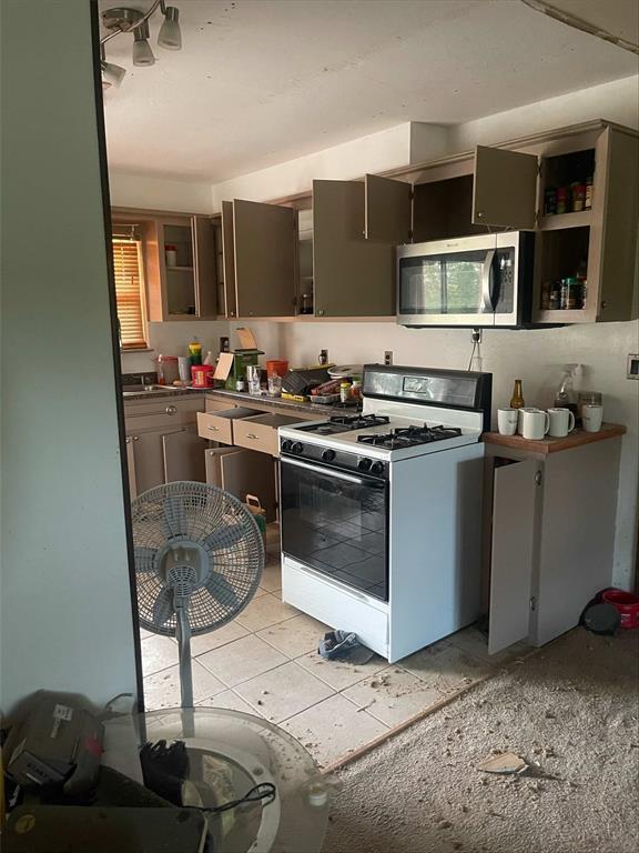 329131 E Lincoln St, Harrah, OK 73045 - kitchen featuring white gas range oven, stainless steel microwave, dark countertops, and open shelves