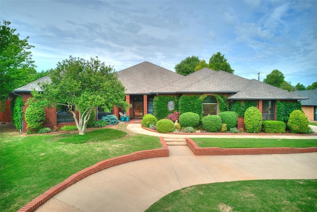 1525 Spring Creek Dr, Yukon, OK 73099 - view of front of house with a front yard, roof with shingles, and brick siding