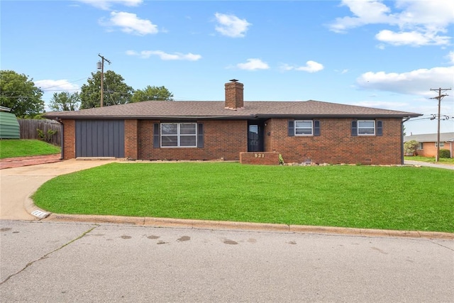 ranch-style home featuring a chimney, driveway, brick siding, and a front yard