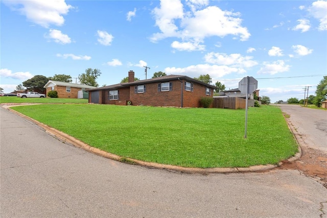 view of side of home with a chimney, a yard, brick siding, and fence