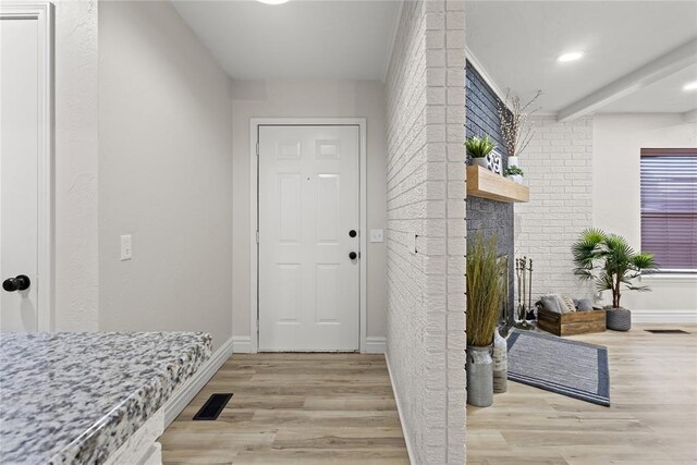 interior space with baseboards, light wood finished floors, a fireplace, and visible vents