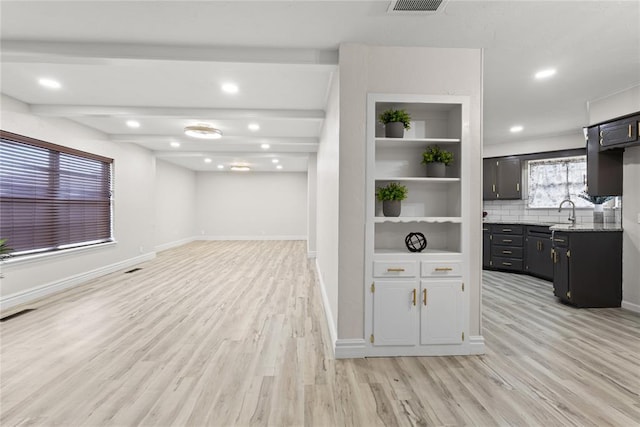 interior space with light wood finished floors, a sink, baseboards, tasteful backsplash, and recessed lighting