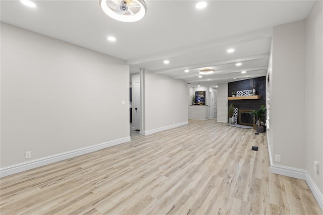 below grade area featuring baseboards, a brick fireplace, recessed lighting, and wood finished floors