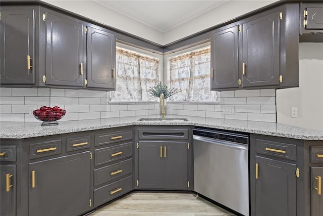 kitchen with stainless steel dishwasher, light wood-style flooring, tasteful backsplash, and a sink