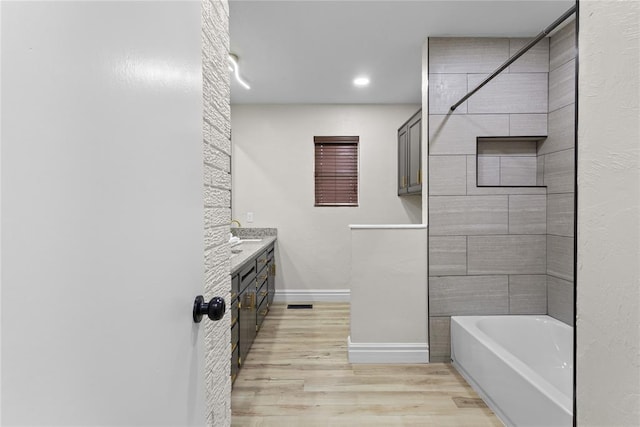 bathroom with wood finished floors, a bathtub, baseboards, walk in shower, and vanity