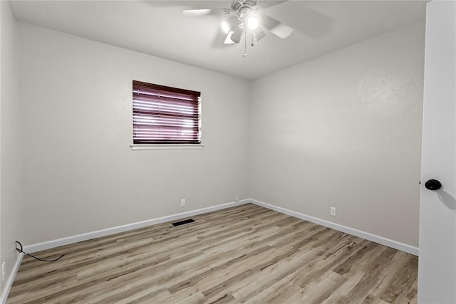 unfurnished room featuring baseboards, visible vents, and wood finished floors