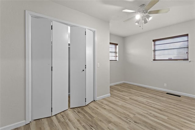 unfurnished bedroom featuring a ceiling fan, baseboards, light wood-type flooring, and visible vents