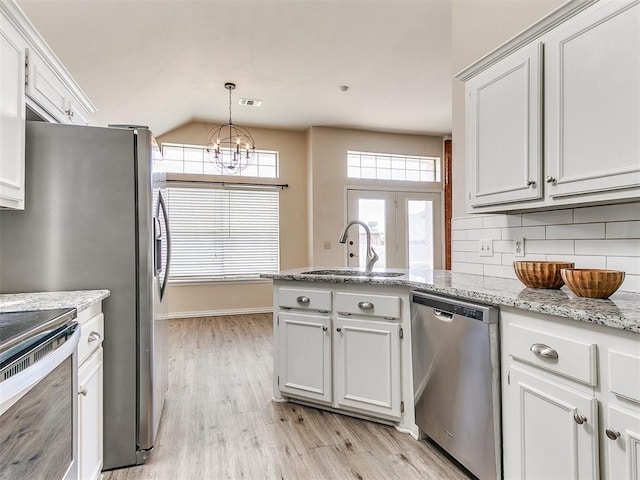 kitchen with stainless steel appliances, a sink, light wood-style floors, a peninsula, and tasteful backsplash