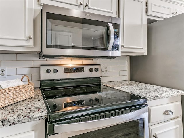 kitchen with appliances with stainless steel finishes, backsplash, white cabinets, and light stone countertops