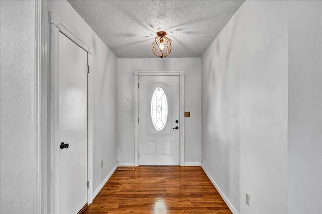 entryway featuring baseboards, a textured ceiling, and wood finished floors