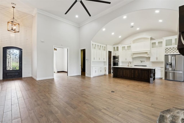 1111 Colonial Ave, Tuttle, OK 73089 - kitchen with ceiling fan with notable chandelier, stainless steel appliances, open floor plan, arched walkways, and light countertops