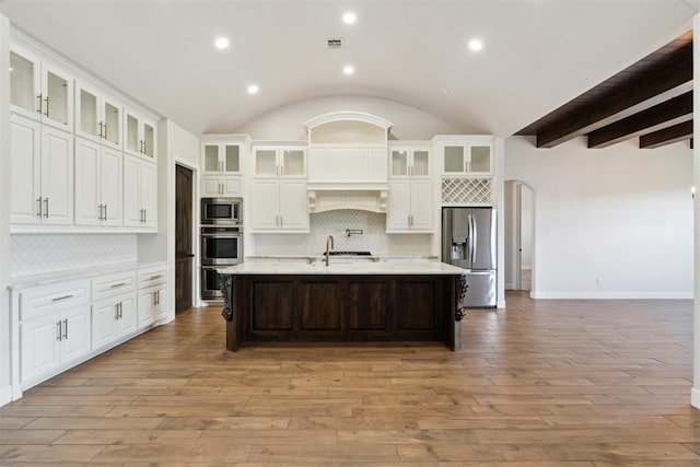 1111 Colonial Ave, Tuttle, OK 73089 - kitchen featuring light wood-style flooring, a kitchen island with sink, white cabinetry, backsplash, and appliances with stainless steel finishes
