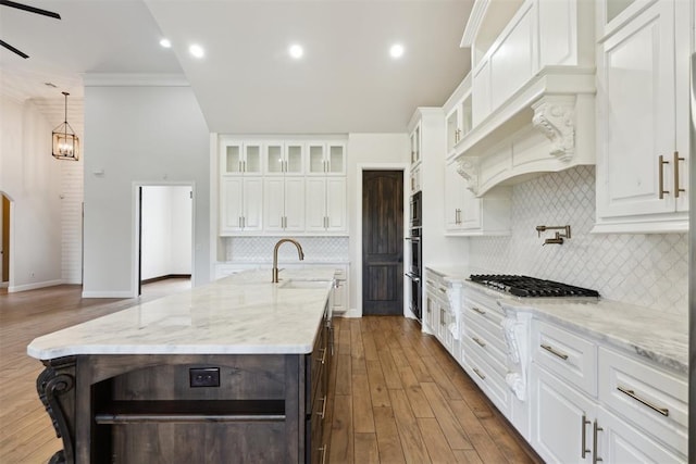 1111 Colonial Ave, Tuttle, OK 73089 - kitchen with a kitchen island with sink, backsplash, stainless steel gas cooktop, and white cabinets