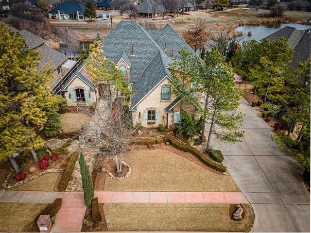 view of front of property with stone siding, a shingled roof, a residential view, and concrete driveway