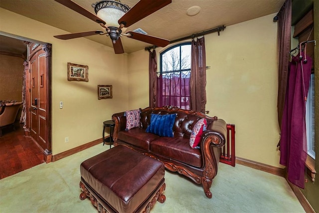living room featuring carpet, baseboards, a ceiling fan, and visible vents