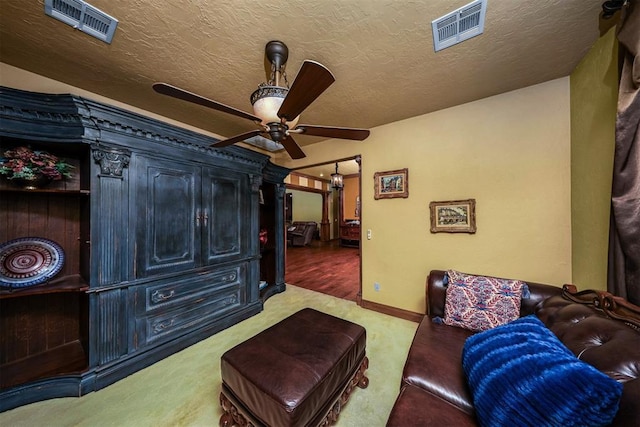 interior space featuring ceiling fan, a textured ceiling, baseboards, and visible vents