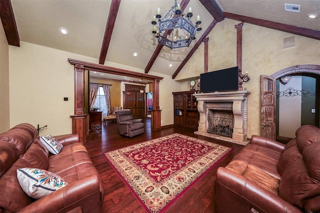 living room featuring an inviting chandelier, wood finished floors, a fireplace, lofted ceiling with beams, and visible vents