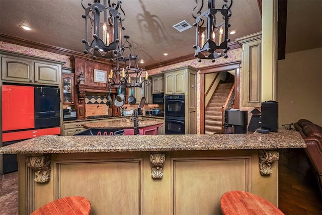 kitchen featuring a peninsula, ornamental molding, visible vents, an inviting chandelier, and dobule oven black