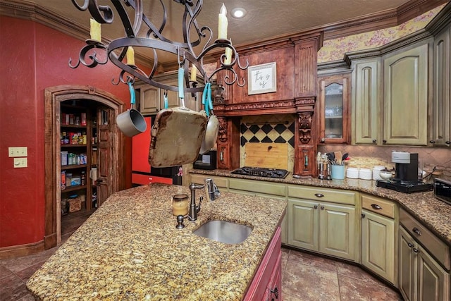 kitchen featuring crown molding, light stone countertops, black gas stovetop, and a sink