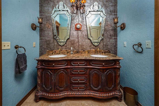 bathroom featuring double vanity, a chandelier, baseboards, and a sink