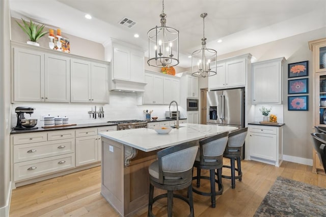 kitchen featuring appliances with stainless steel finishes, recessed lighting, backsplash, hanging light fixtures, and an island with sink