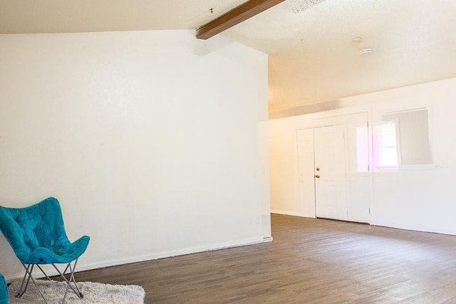 foyer entrance featuring lofted ceiling with beams, baseboards, and wood finished floors