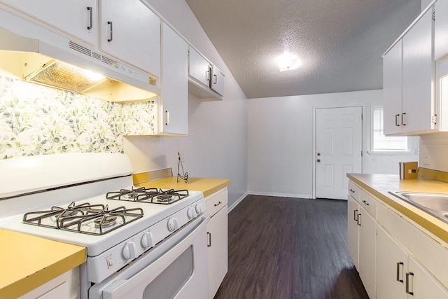 kitchen featuring white range with gas stovetop, under cabinet range hood, baseboards, dark wood finished floors, and light countertops