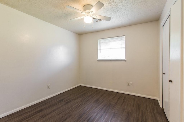 unfurnished bedroom featuring a closet, a textured ceiling, baseboards, and dark wood-style floors