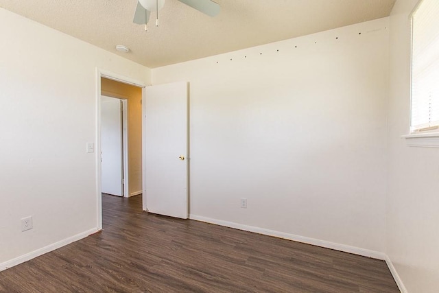 empty room featuring a ceiling fan, dark wood-style flooring, and baseboards