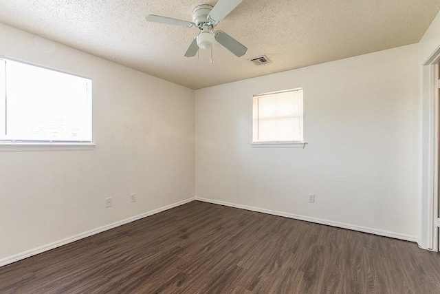 empty room with a textured ceiling, visible vents, ceiling fan, dark wood-style floors, and baseboards