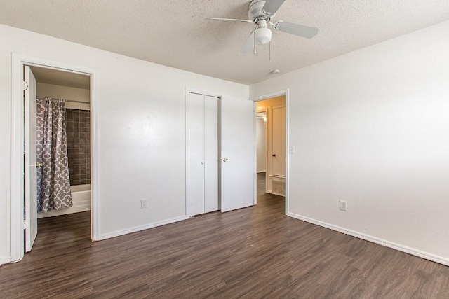 unfurnished bedroom with a closet, a textured ceiling, dark wood-style flooring, ceiling fan, and baseboards