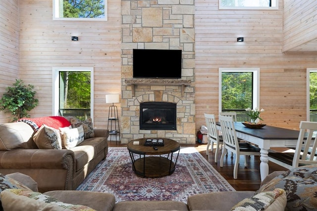 living room featuring wooden walls, wood finished floors, a fireplace, and a high ceiling