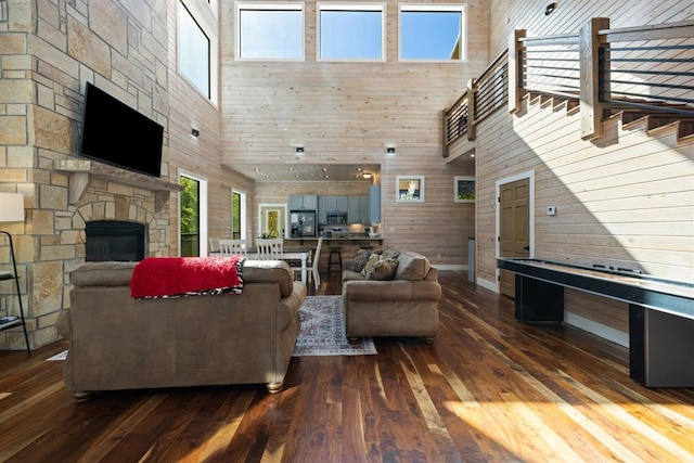 living area with a high ceiling, a fireplace, wood walls, stairway, and hardwood / wood-style flooring