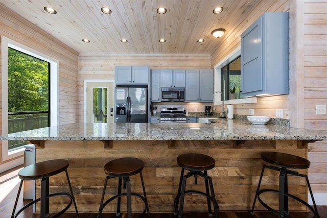 kitchen with a sink, a peninsula, stainless steel appliances, recessed lighting, and light stone countertops