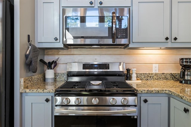 kitchen with decorative backsplash, stainless steel appliances, and light stone countertops