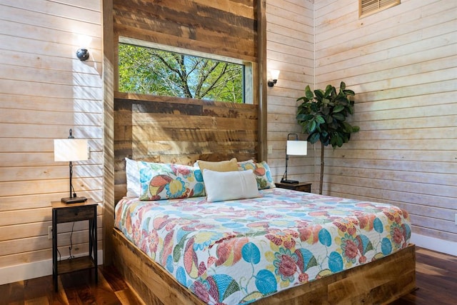 bedroom featuring wood walls, baseboards, visible vents, and wood finished floors