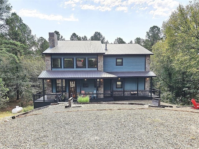 rustic home featuring a porch, stone siding, metal roof, and a chimney