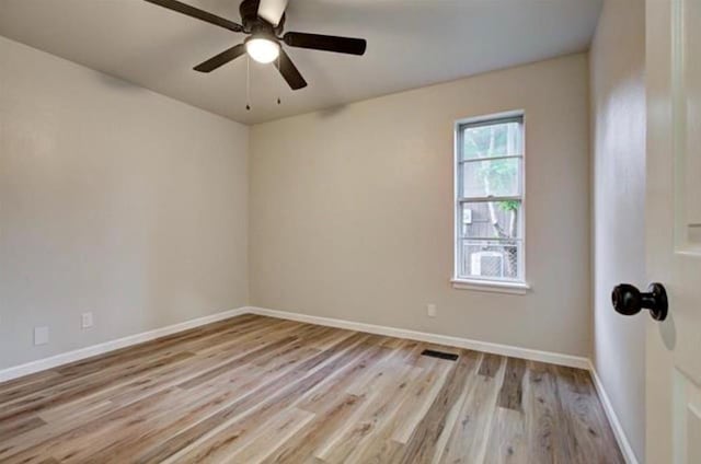 spare room with light wood-type flooring, visible vents, baseboards, and a ceiling fan
