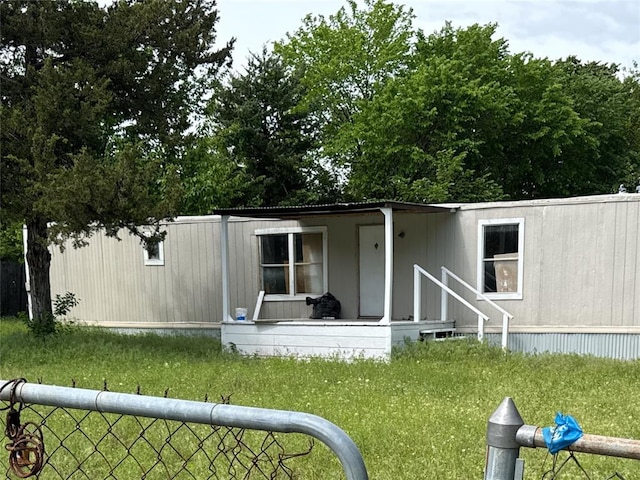 back of property with a lawn and fence